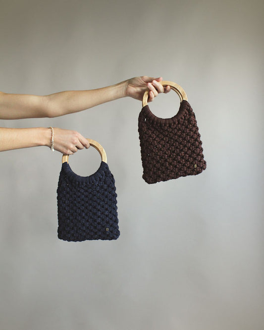 Gala Bag azul marino y marrón, sujetados por las asas de madera.